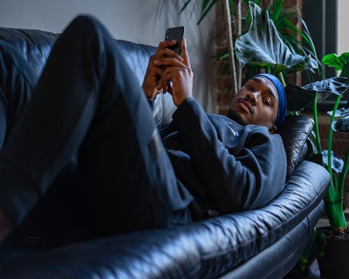 A person resting holding a phone, relaxing on a sofa in a modern apartment